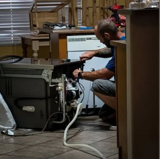 Technician working on a dishwasher pulled out from under the counter