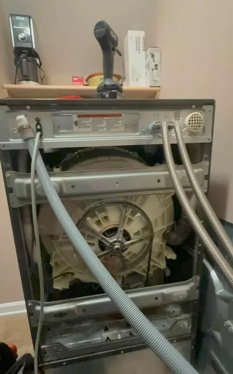 Washer with the cabinet removed showing hoses, pump, and wiring for electrical testing